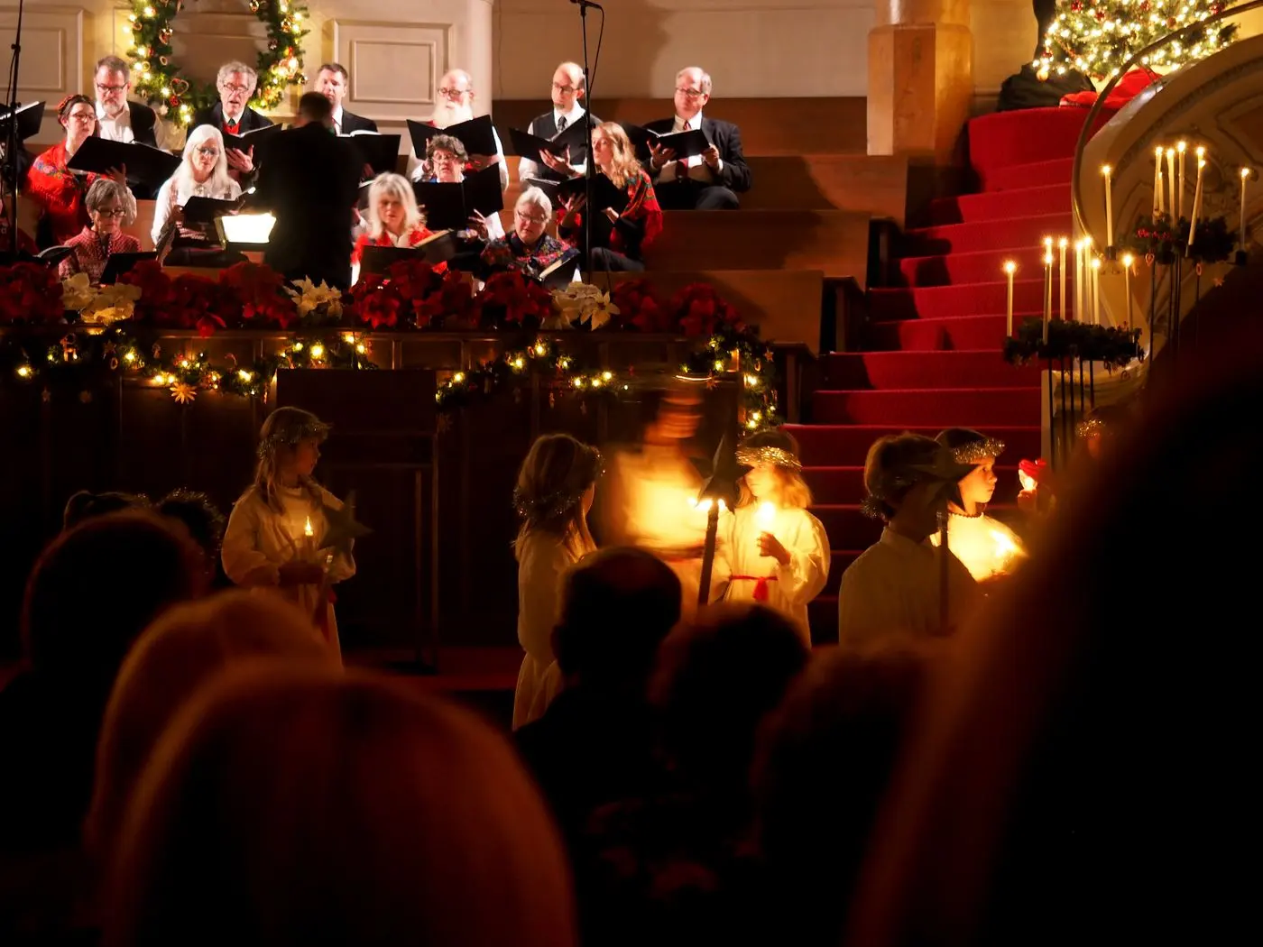 Kor og barn med levende lys under en julekonsert i en kirke