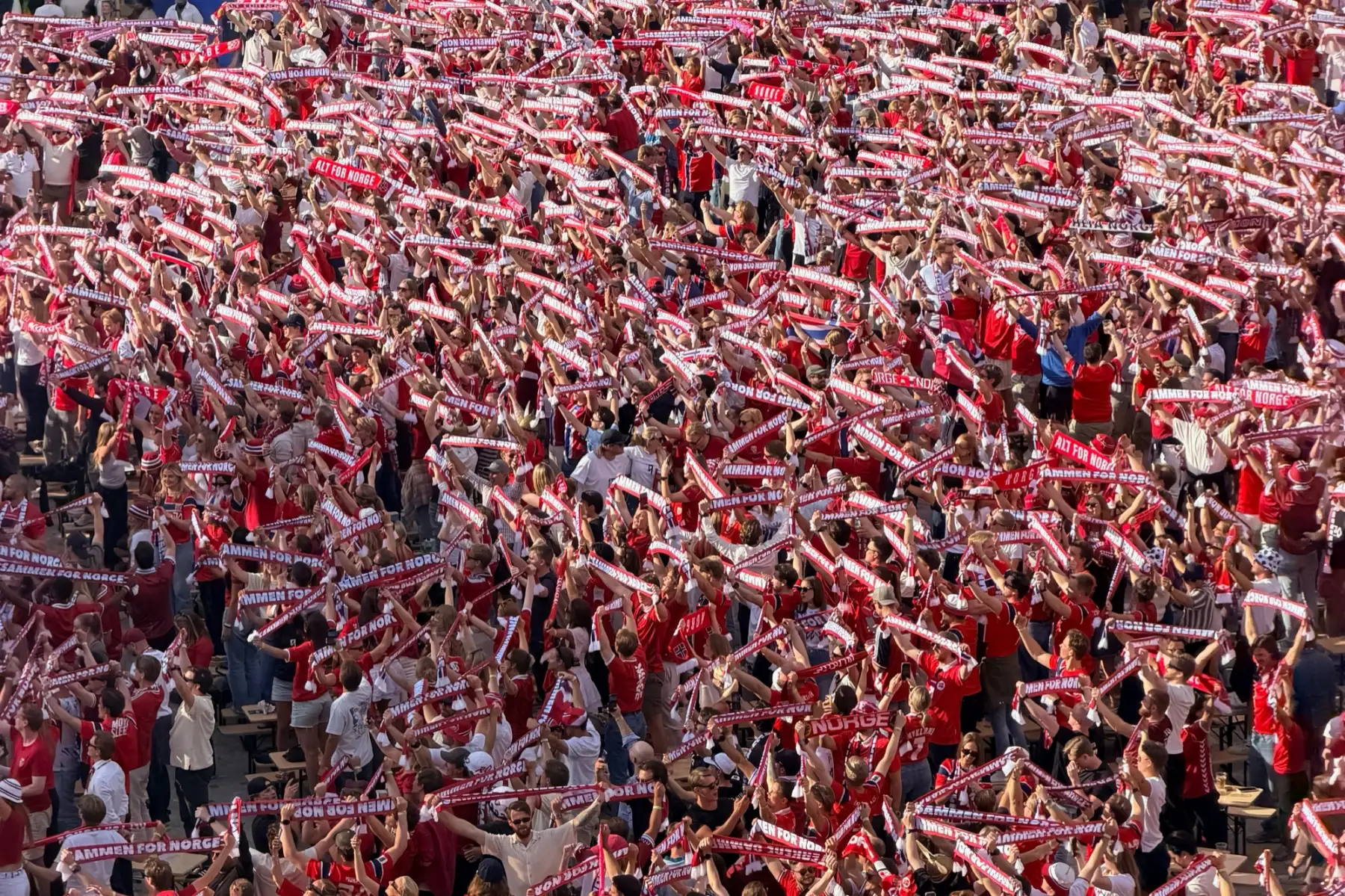 Norske supportere i rødt holder skjerfene over hodet på tribunen